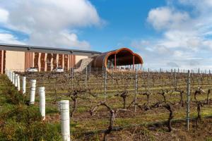 a vineyard behind a fence with a building in the background at Port Lincoln Marina Waterfront Apartment in Port Lincoln