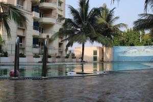 een zwembad voor een gebouw met palmbomen bij Nath's Residency in Puri