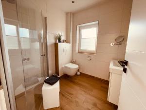 een badkamer met een toilet, een douche en een wastafel bij Ferienwohnungen MEERAUSZEIT Norddeich in Norddeich