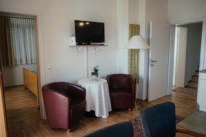 ein Wohnzimmer mit 2 Stühlen, einem Tisch und einem TV in der Unterkunft Gästehaus Jeindl in Hartmannsdorf
