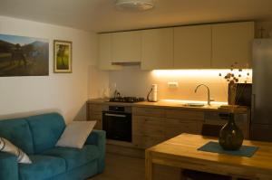 a living room with a blue couch and a kitchen at Barić Draga in Barić Draga