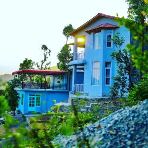 una casa azul sentada en la cima de una colina en Raahi Cottages Mukteshwar, en Mukteshwar