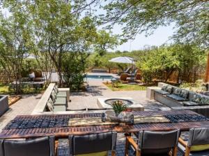 un patio con mesa, sillas y piscina en Muunga Bush Lodge & Spa en Hoedspruit