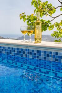 a bottle of wine and glasses next to a swimming pool at Karpathos View Villa in Karpathos