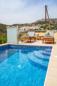 a swimming pool with two chairs and a table at Karpathos View Villa in Karpathos