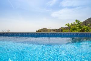 a swimming pool with blue water and trees in the background at Karpathos View Villa in Karpathos
