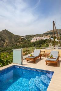 a swimming pool with two lounge chairs next to at Karpathos View Villa in Karpathos