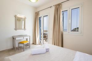 a bedroom with a bed and a desk and windows at Karpathos View Villa in Karpathos +37 photos
