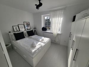 biała sypialnia z białym łóżkiem i oknem w obiekcie PRZYTULNY APARTAMENT Z KOMINKIEM PRZY JEZIORZE w Bornem-Sulinowie