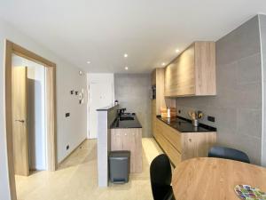 eine Küche mit Holzschränken und einem Tisch in der Unterkunft El Piso - Los Boliches Full Renovated Apartment in Fuengirola