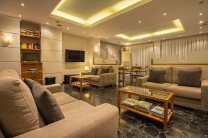 a living room with couches and a tv and a table at Lilia Hotel in Piraeus