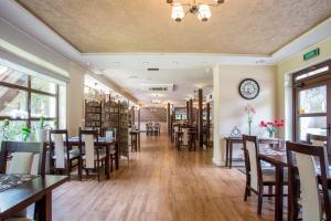 a restaurant with tables and chairs and a clock on the wall at Zajazd Drogorad Restauracja i Noclegi in Mielno