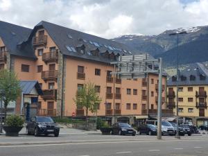 um grande edifício de apartamentos com carros estacionados em frente em ES CÒVES em Vielha