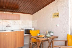 a small kitchen with a wooden table and yellow chairs at Esperides Studios-Seaside Stay with View in Syvota in Syvota