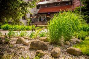 um jardim com pedras e plantas em frente a um edifício em Zajazd Drogorad Restauracja i Noclegi em Mielno