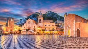 a group of buildings in a square in front of a mountain at Sweet House Taormina in Taormina
