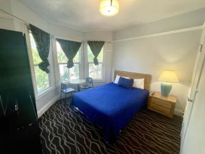 a bedroom with a blue bed and two windows at Twin Peaks Hotel in San Francisco