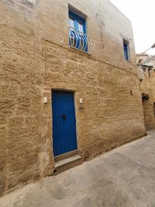 eine blaue Tür an der Seite eines Backsteingebäudes in der Unterkunft B&S Accommodation Apartment 601 in Hal Ghaxiak