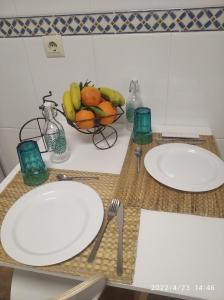 dos platos blancos en un mostrador con un bol de fruta en apartamento melide, en Melide