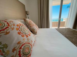 a bedroom with a bed with pillows and a window at FAY Victoria Beach in Rincón de la Victoria