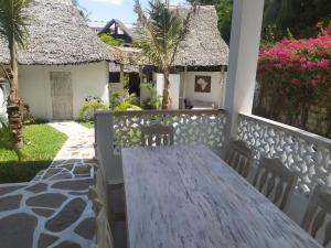 una mesa de madera en el balcón de una casa en Garoda House Turtle Bay [ Jacuzzi ☆☆☆☆☆ ] Kilifi, en Watamu