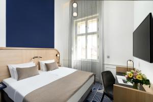 a bedroom with a bed and a tv and a chair at Hotel Oktogon Haggenmacher in Budapest