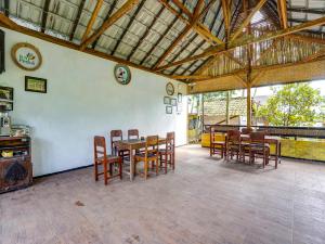 une salle à manger avec des tables et des chaises en bois dans un bâtiment dans l'établissement OYO Homes 91103 Syariah Desa Wisata Lembah Gunung Tumpeng, à Sumberwaras