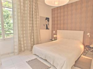 sypialnia z białym łóżkiem i oknem w obiekcie Villa Saint Charles w mieście Juan-les-Pins