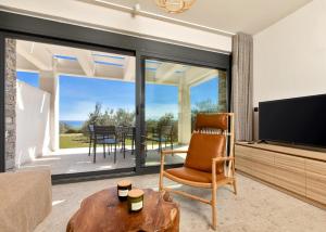 a living room with a television and a chair and a table at Casa Del Olivar in Develíkia