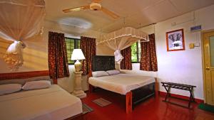 a bedroom with two beds and a lamp and windows at S and K Safari Village Hotel - Wasgamuwa in Wasgamuwa
