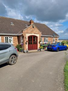 deux voitures garées devant une maison avec une porte rouge dans l'établissement Willowcroft, à Alkborough