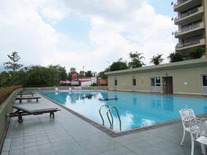 a large swimming pool with tables and chairs next to a building at Great Location Living, Modern 2-Bed Apartment with Pool & Gym Access, All Amenities in Sri Jayewardenepura Kotte