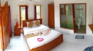 a bedroom with two beds and a bathroom with a shower at Kartika's House in Ubud