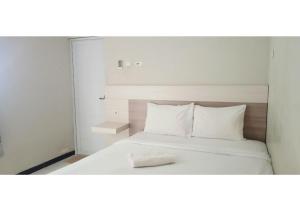 a white bed with a towel on top of it at Bumi Banyu Bening Syariah by ecommerceloka in Surabaya