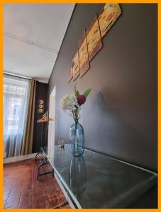 a glass table with a vase with flowers on it at Gîtes du petit familistère Landrecies in Guise