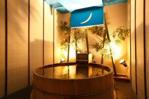 Tabist Hotel Colosseum Inn Tateshina في تاتيشينا: برميل خشبي كبير في غرفة مع علم الليل