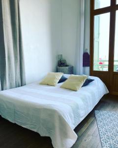 een bed met witte lakens en kussens in een slaapkamer bij Villa les Fleurs Appartement en front de mer in Mers-les-Bains