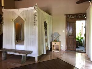 1 dormitorio con cama con dosel y puerta de madera en Villa KAROUNA, en Sukawati 34 fotos más