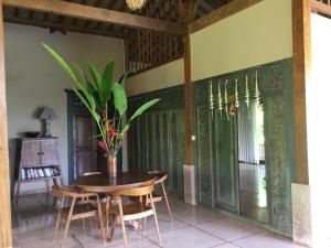 un comedor con mesa, sillas y una planta en Villa KAROUNA, en Sukawati