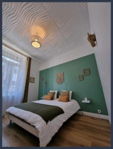 um quarto com uma cama grande e uma parede verde em Gîtes du petit familistère Landrecies em Guise