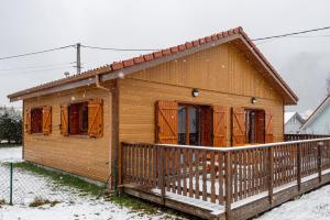 una pequeña casa de madera con nieve en el porche en Macazoline, en Xonrupt-Longemer