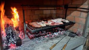 a grill with meat and other food in a fireplace at Cabañas La Catalana in Tandil