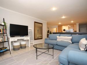 a living room with a blue couch and a tv at Go2Boa Luxury Apartment in Mossel Bay