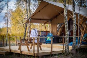 a tent in the woods with a table and chairs at Kaskada Glamping in Łódź