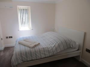 a white bedroom with a bed with two towels on it at Matilda's wee Hutte in Daventry