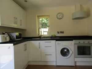 a kitchen with a washing machine and a clock on the wall at Matilda's wee Hutte in Daventry