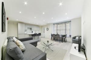 sala de estar con sofá gris y cocina en Chic Apartment by Hyde Park, en Londres