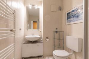 a white bathroom with a sink and a toilet at Haus Knechtsand, Whg 447 in Duhnen
