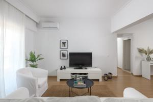 a white living room with a tv and a table at Harmony Elegant Central Apartment in Rhodes Town