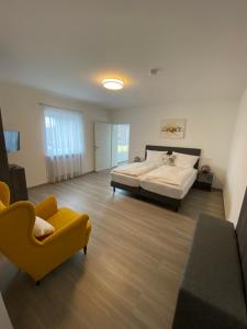 a large bedroom with a bed and a yellow chair at KM Hotel Murtal in Knittelfeld